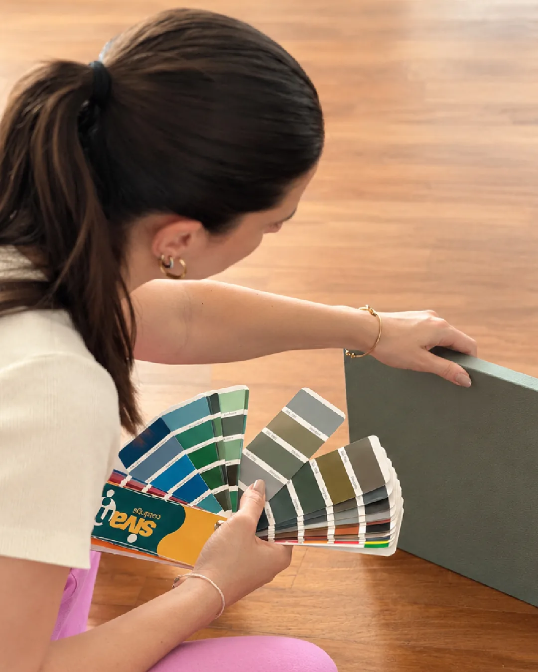 La scelta dei colori sul parquet: una mazzetta aperta accanto a un pannello verde salvia.
